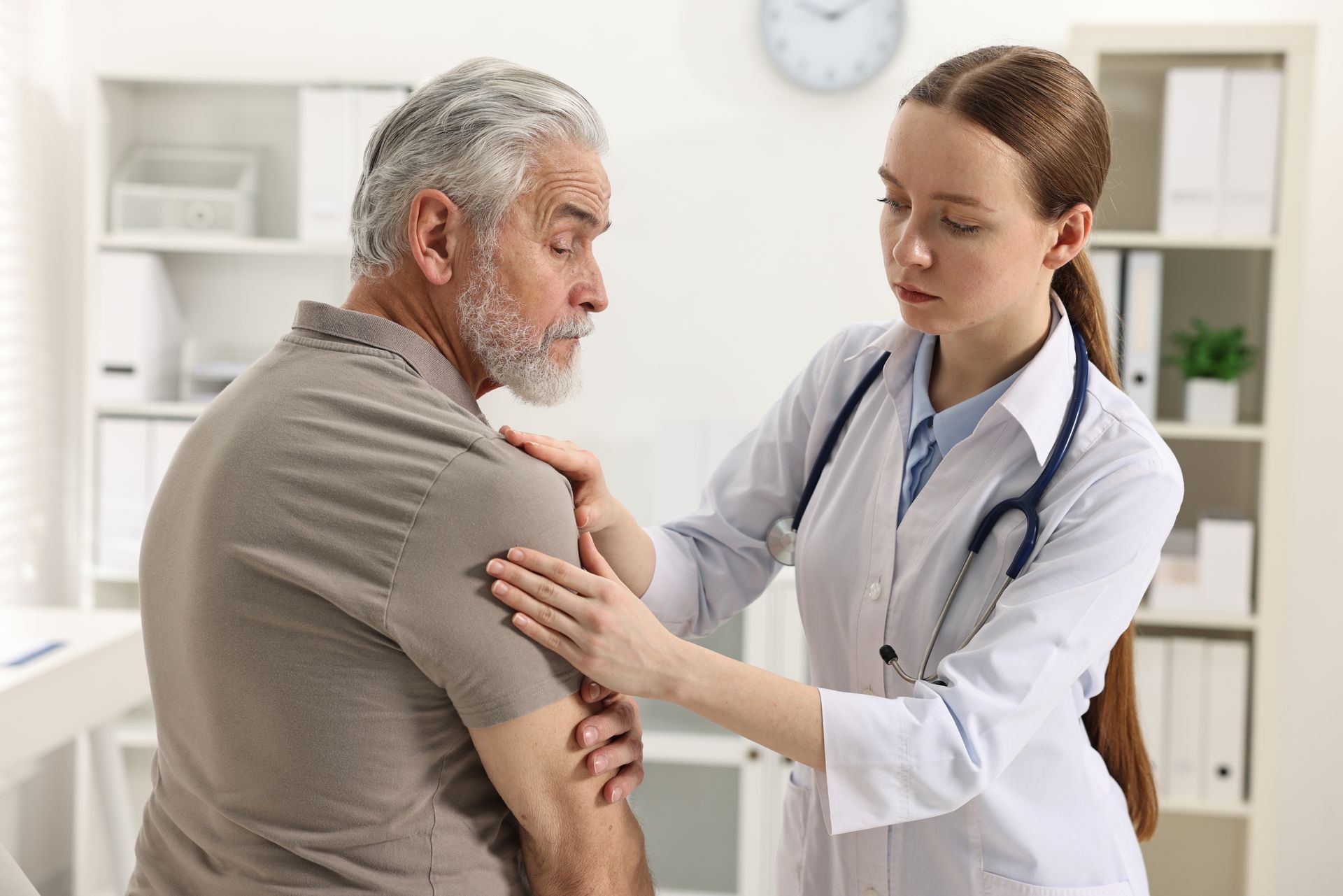 A doctor is examining a patient 's shoulder in a hospital.