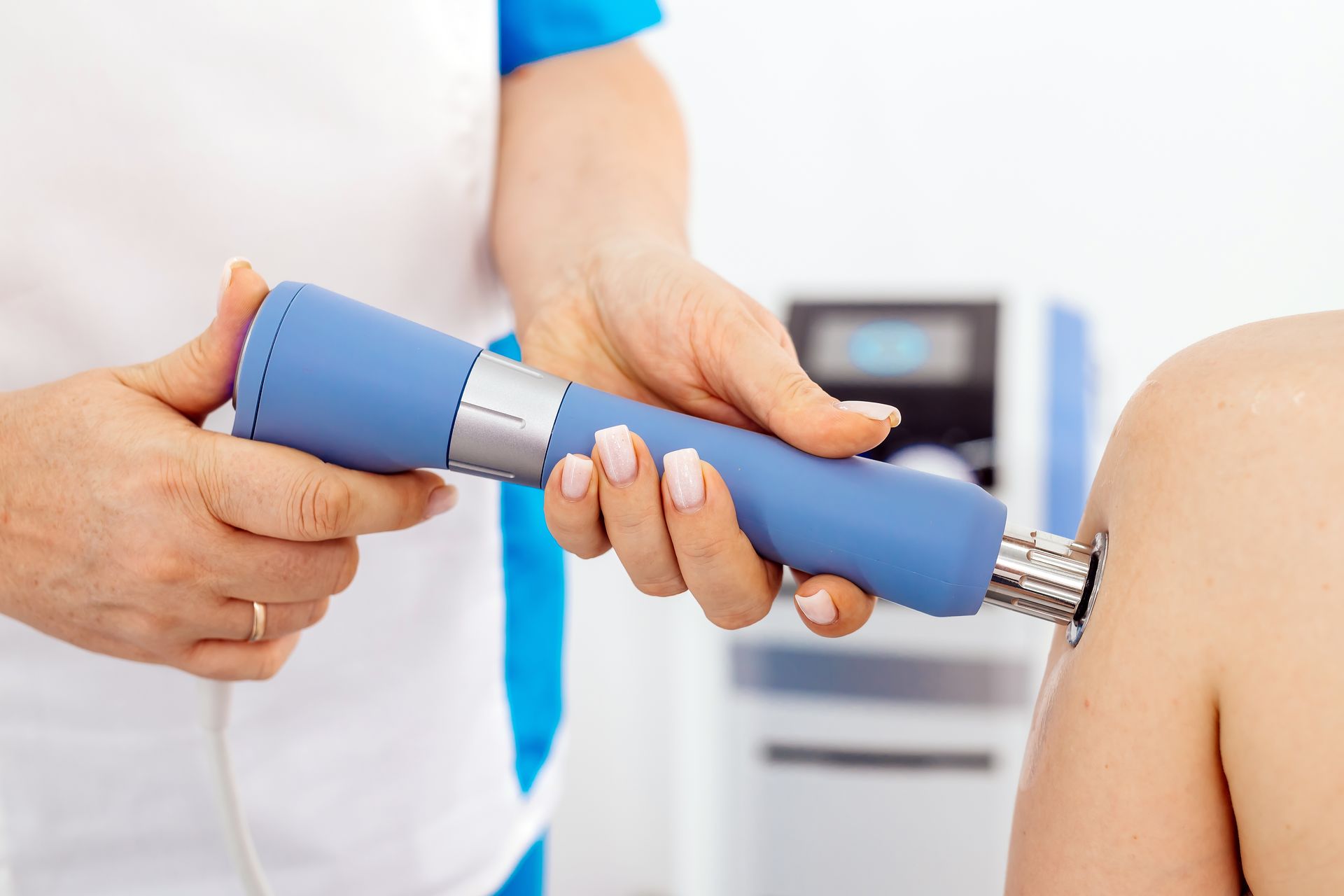 A person is using a machine on another person 's shoulder.