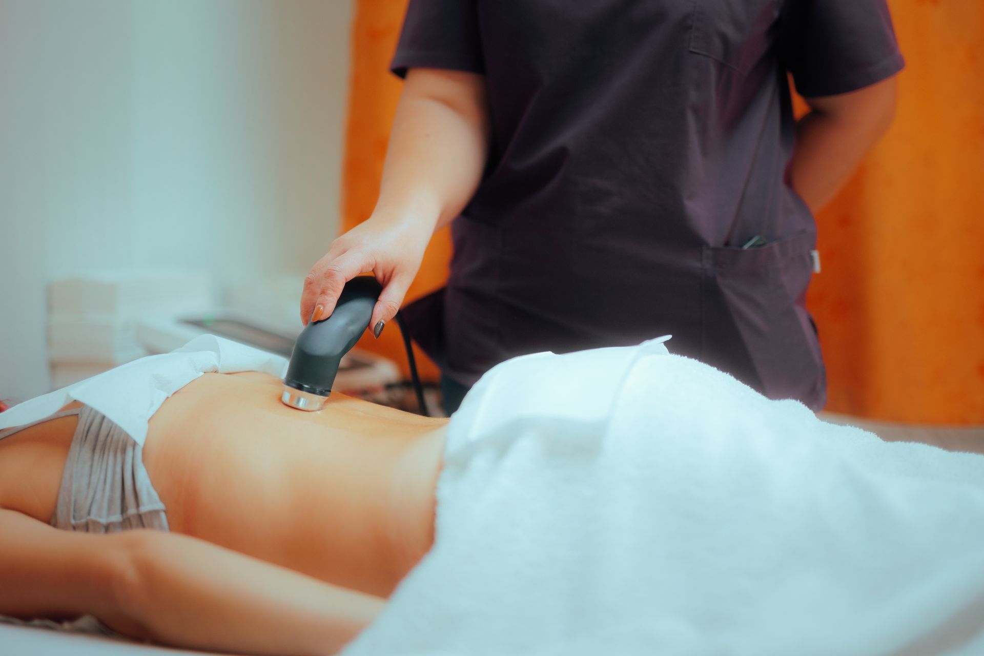 A woman is laying on a bed getting a massage from a massage therapist.
