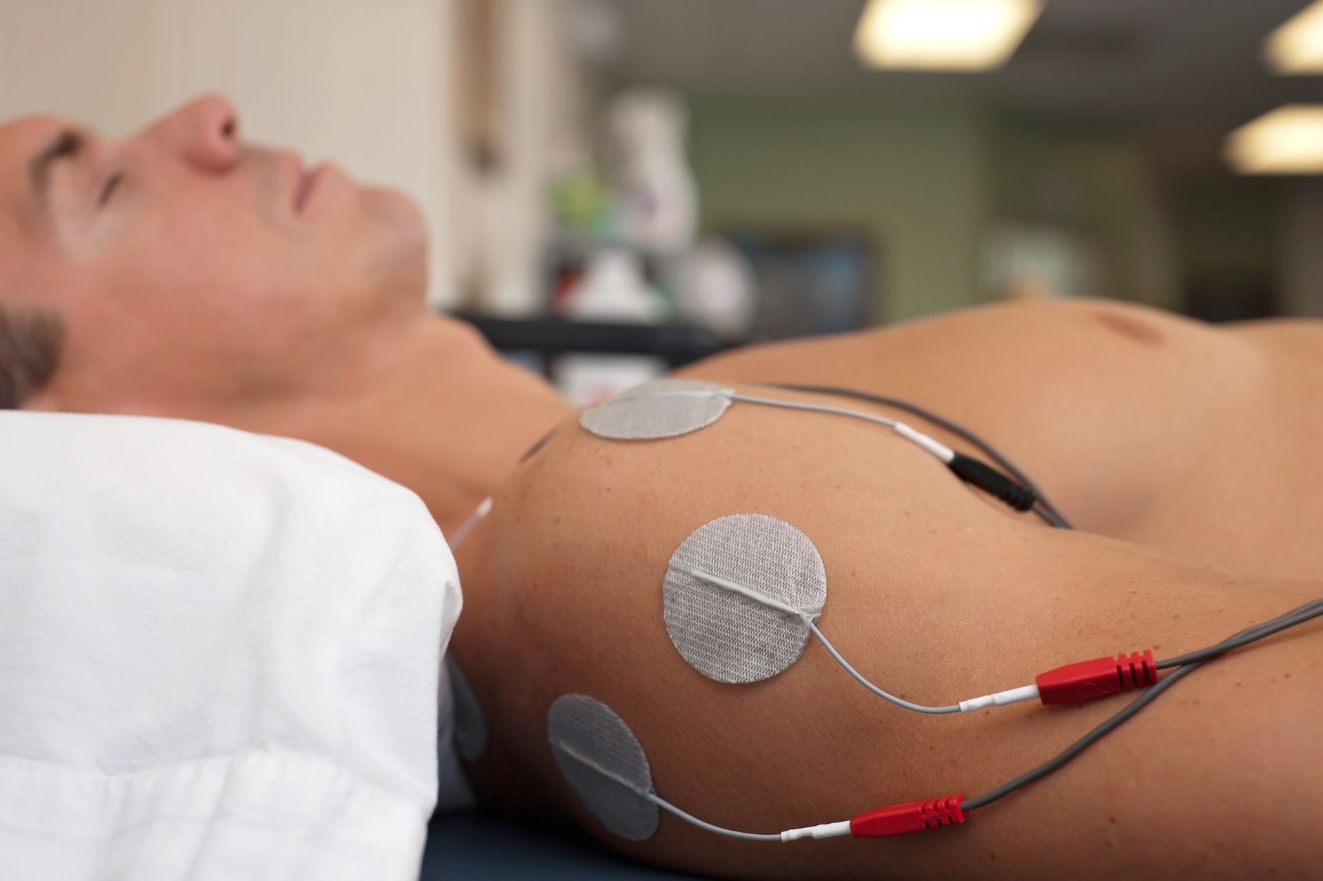 A man is laying on a bed with electrodes on his chest