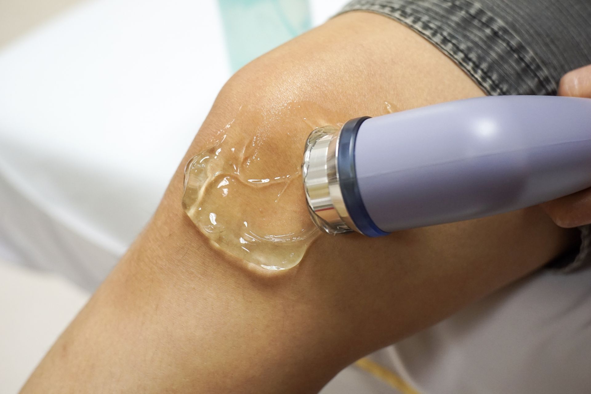 A person is applying gel to their knee with a device.