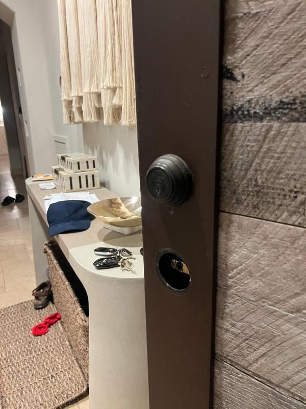 Brown door with lock and keyhole. Keys and items on a nearby table.