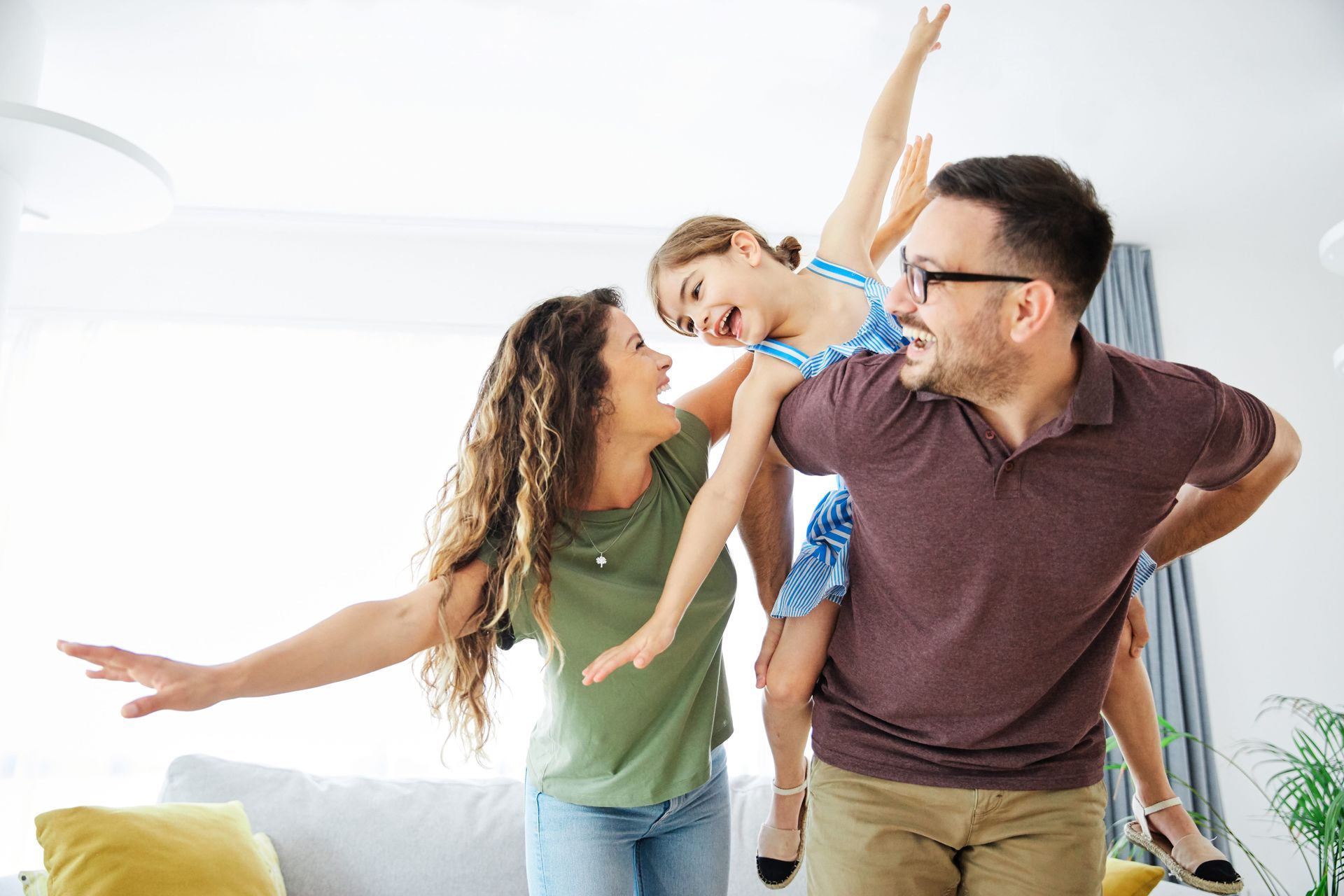 Family laughing and posing playfully on a couch in a bright living room