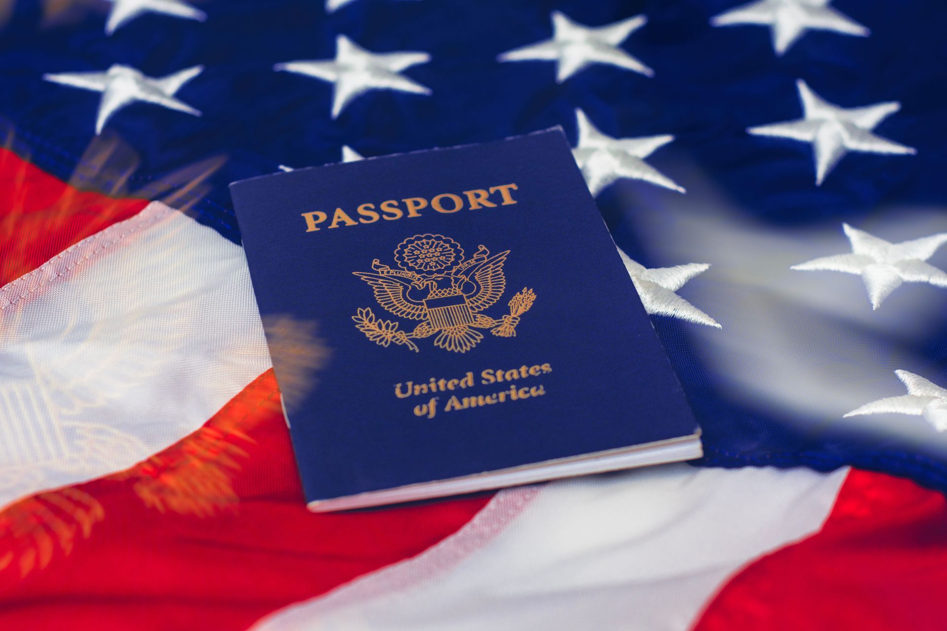 A dark blue United States passport rests on a folded American flag.