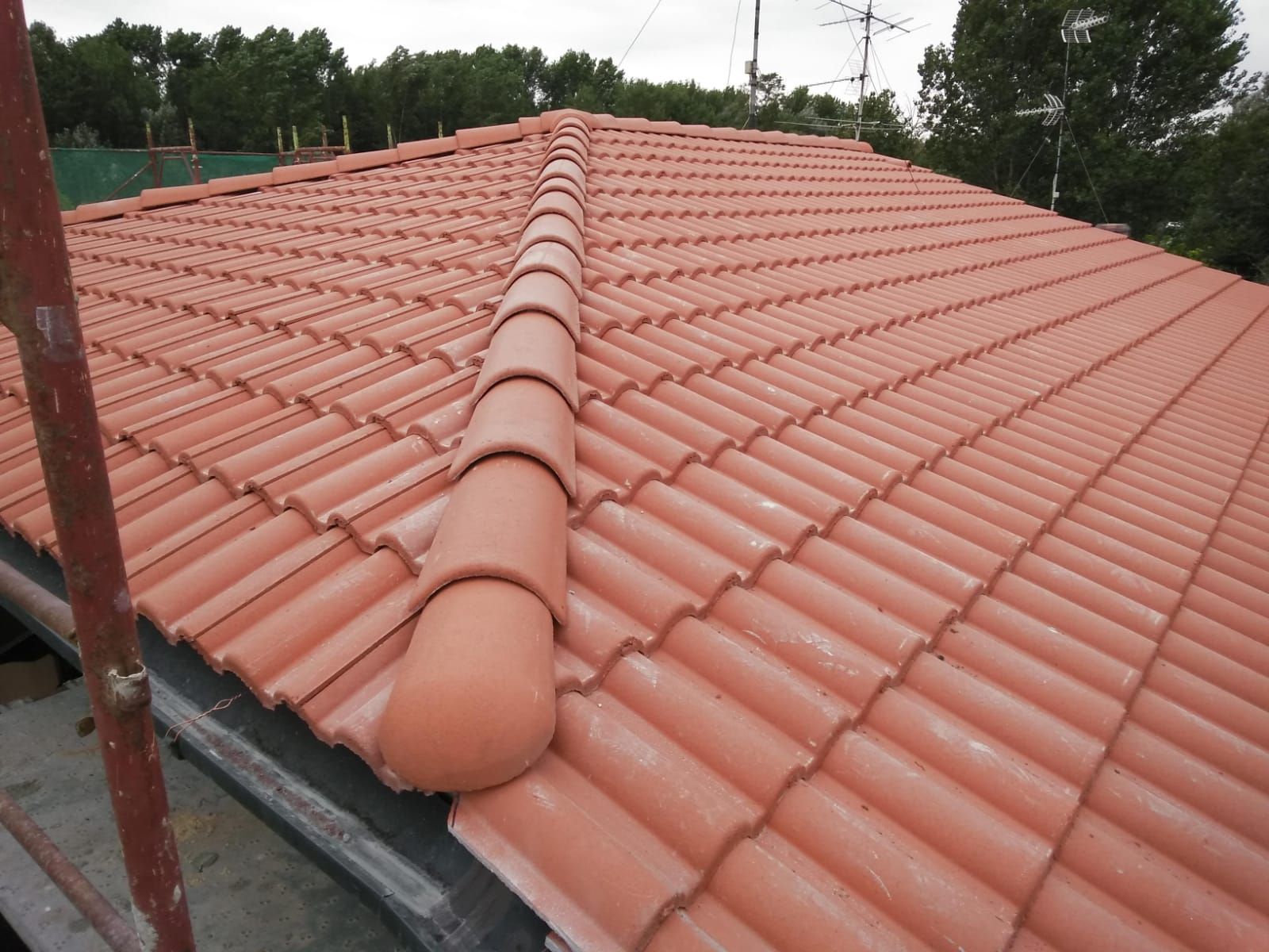 Vista ravvicinata di un tetto di tegole color terracotta appena installato, con colmo centrale.