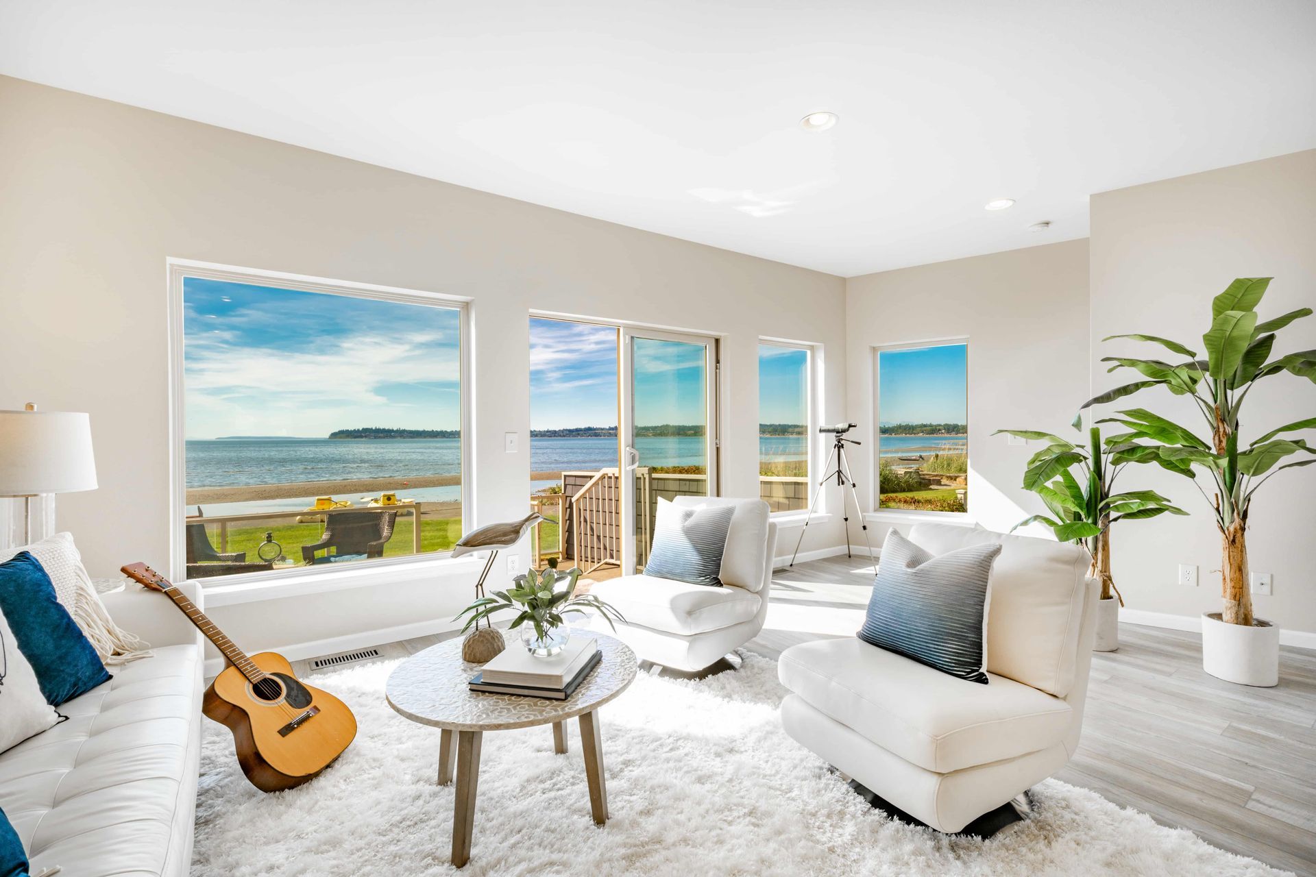 A living room with a guitar on the floor and a view of the ocean.