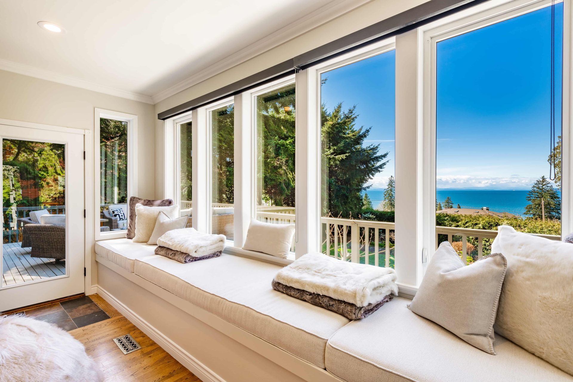 A large window seat in a living room with a view of the ocean.