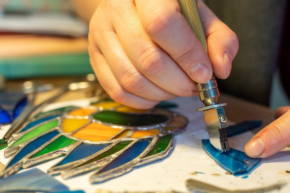 A Person Is Cutting A Piece Of Stained Glass With A Pair Of Scissors — Townsville Stained Glass In Cairns, QLD 