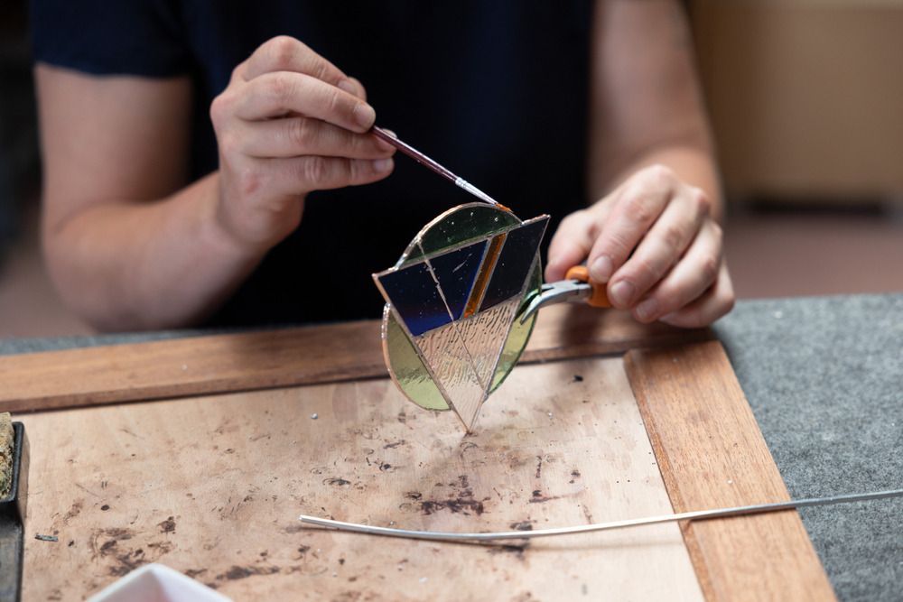 A Person Is Making A Stained Glass Window With A Brush — Townsville Stained Glass In Townsville, QLD