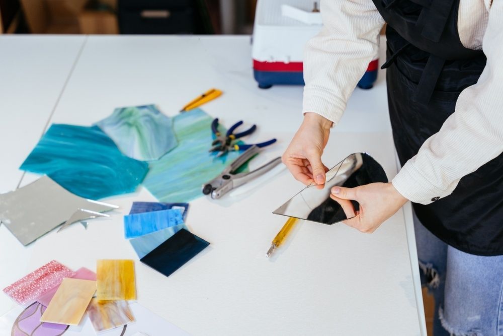 A Person Is Cutting A Piece Of Glass On A Table — Townsville Stained Glass In Cairns, QLD 