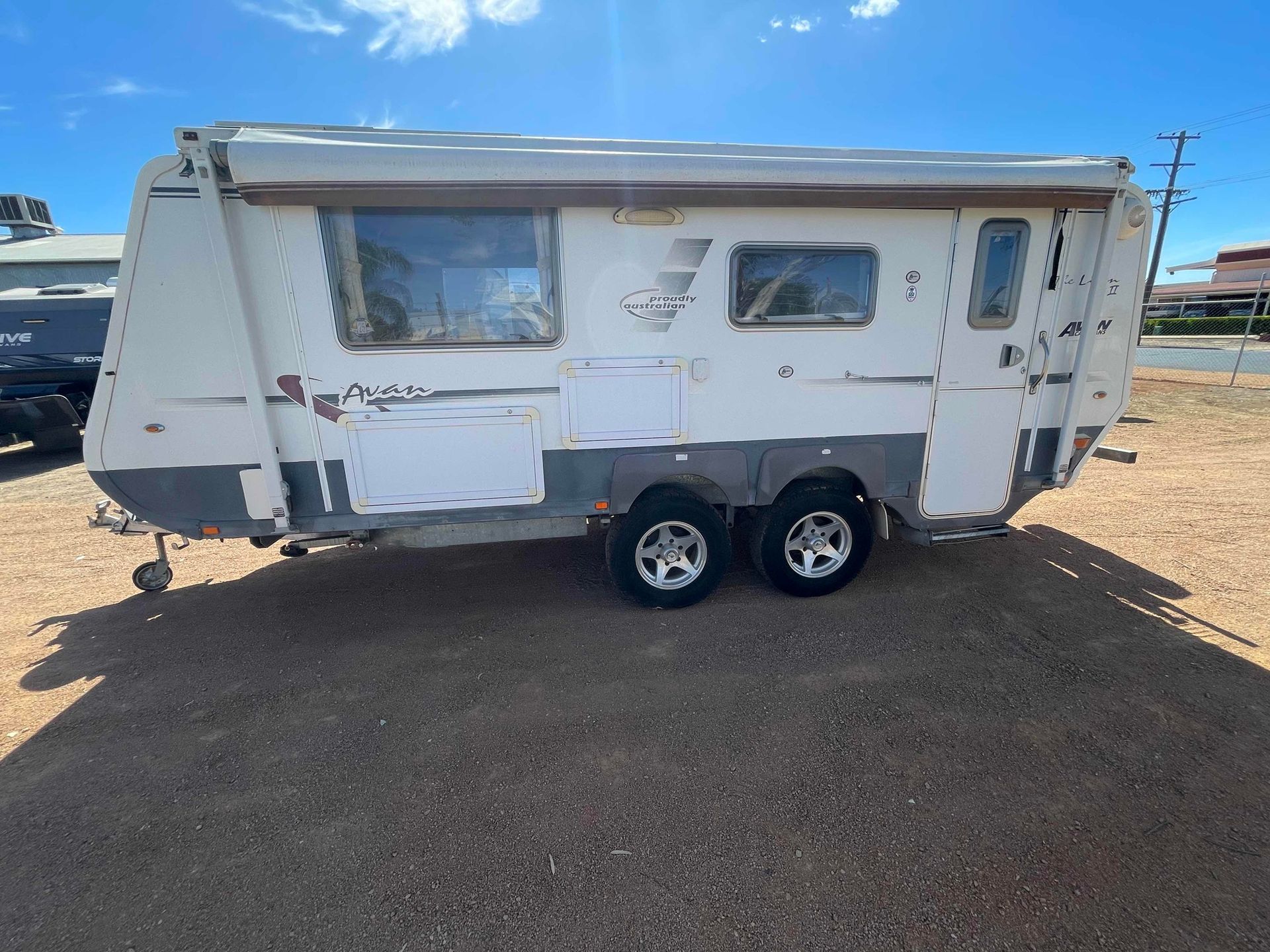 Weathered White Camper Trailer With Two Axles Parked on Asphalt — B & C Caravan Service Pty Ltd In Dubbo, NSW