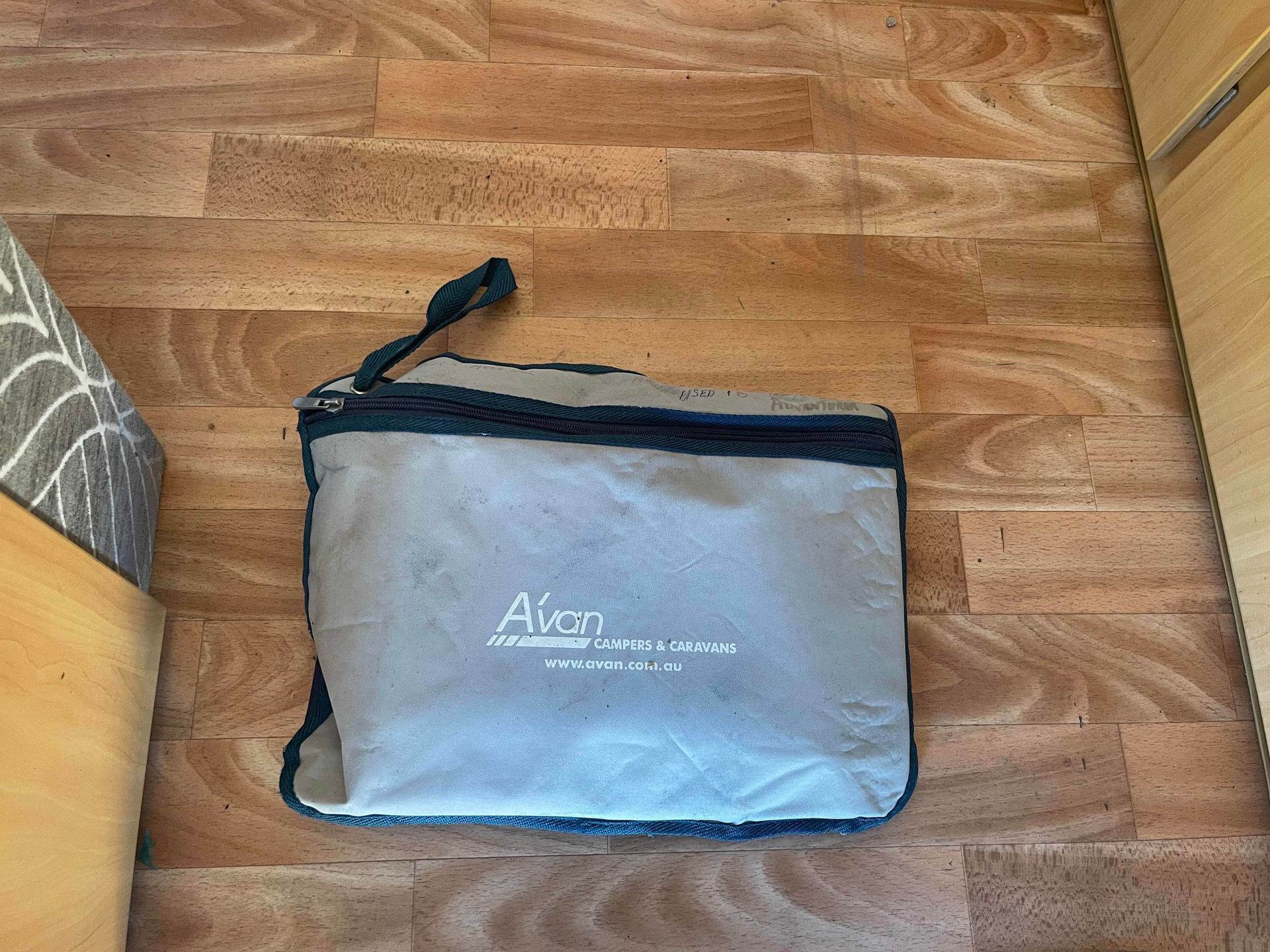 Gray Zippered Pouch With Black Trim on a Wooden Floor — B & C Caravan Service Pty Ltd In Dubbo, NSW