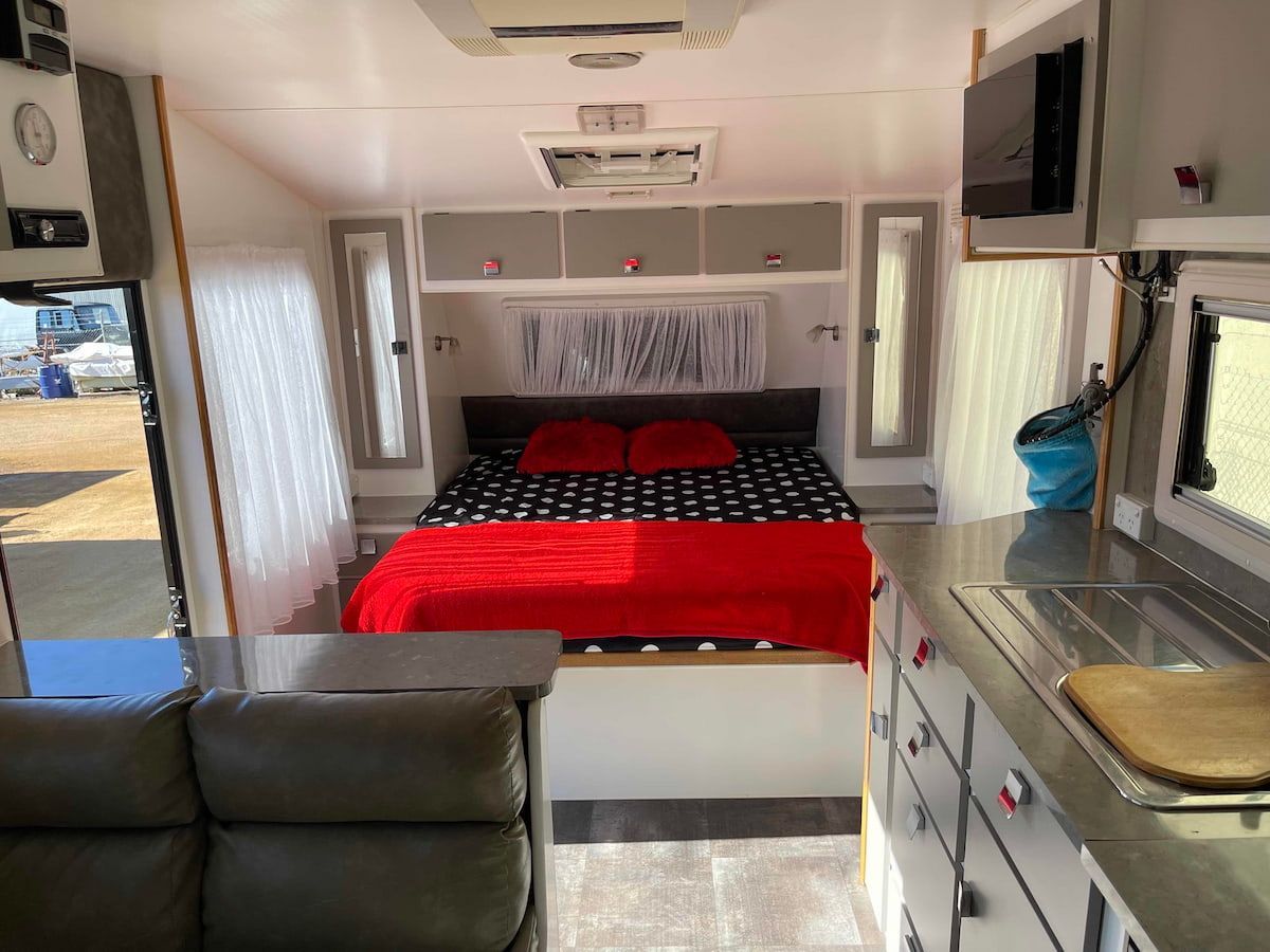 Compact Camper Interior With a Bed, Red Blanket, Gray Cabinets — B & C Caravan Service Pty Ltd In Dubbo, NSW