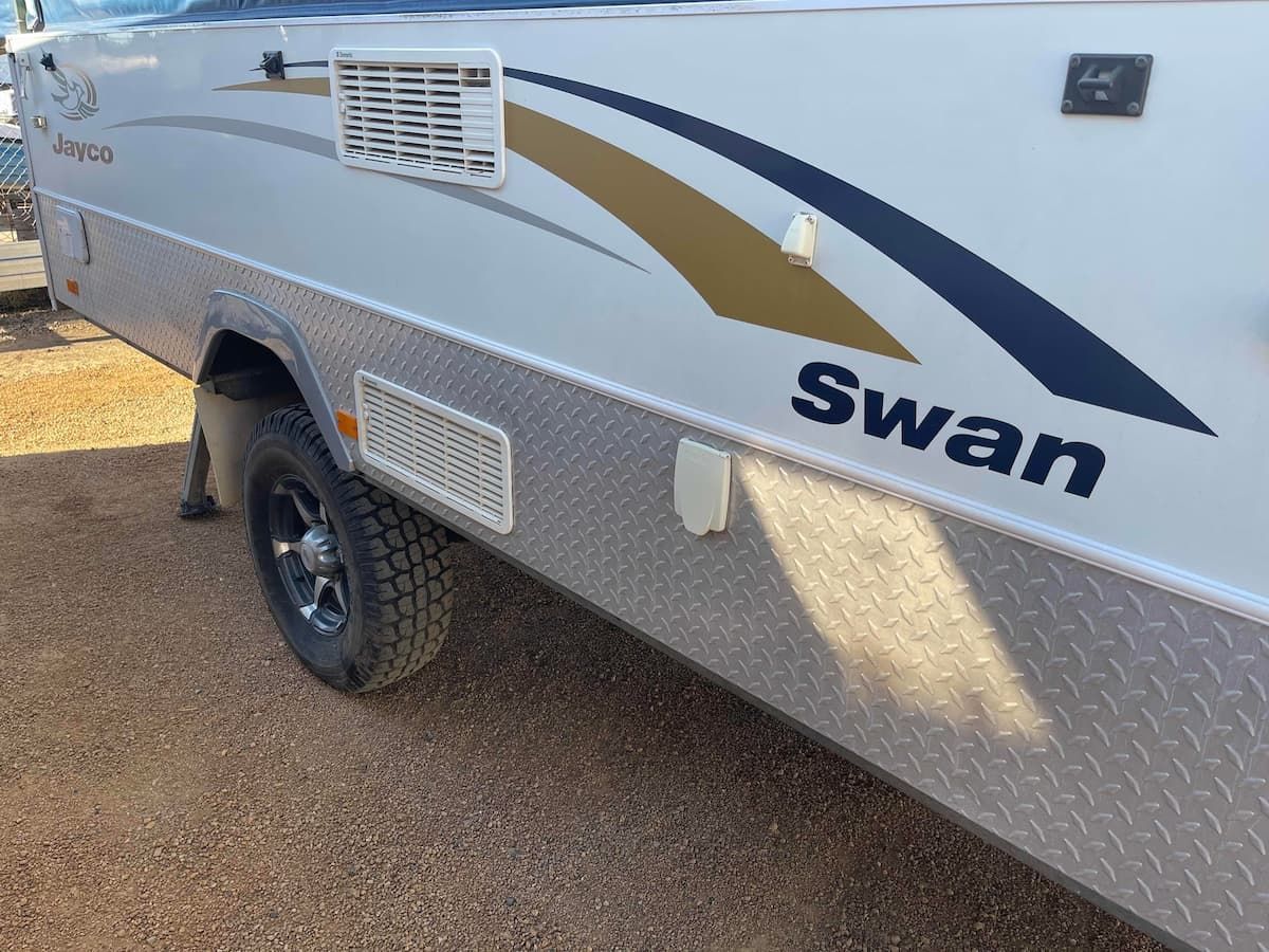 White Swan Caravan With Gold and Navy Swooshes Parked — B & C Caravan Service Pty Ltd In Dubbo, NSW