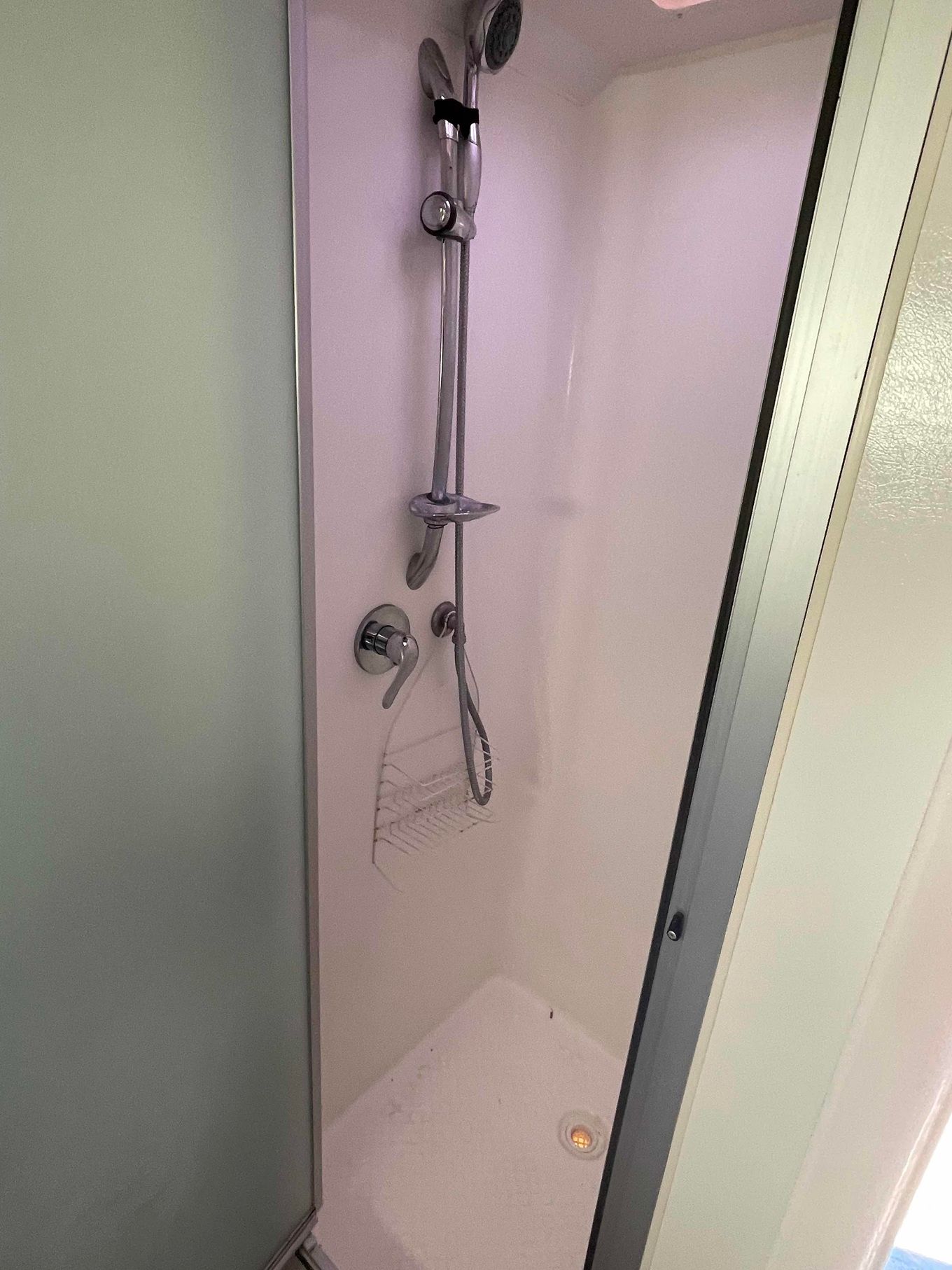 Small Shower Stall with White Walls, a Chrome Showerhead, and A Corner Shelf — B & C Caravan Service Pty Ltd In Dubbo, NSW