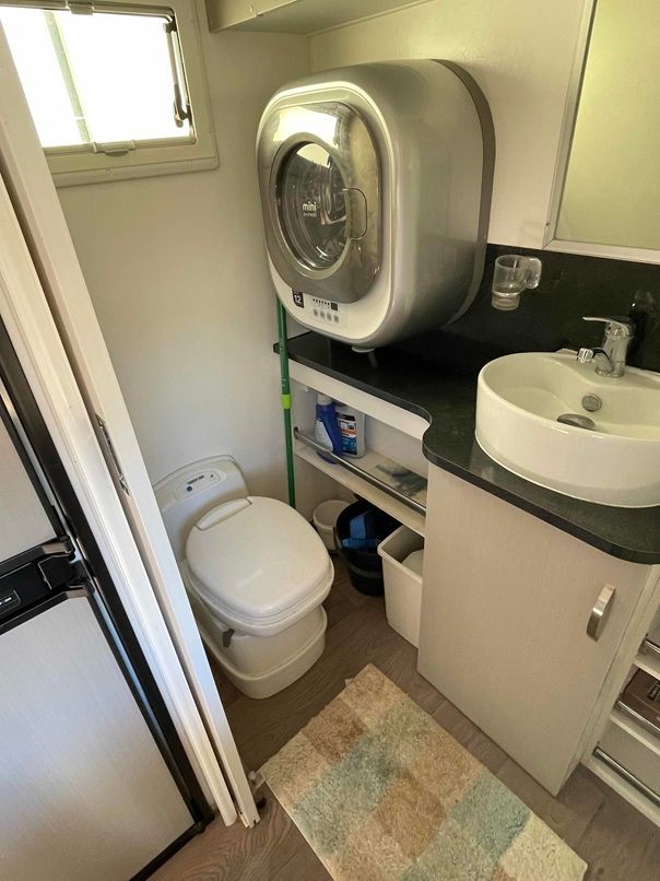 Compact RV Bathroom with Toilet, Sink, Wall Mounted Washer, and Shower Door — B & C Caravan Service Pty Ltd In Dubbo, NSW