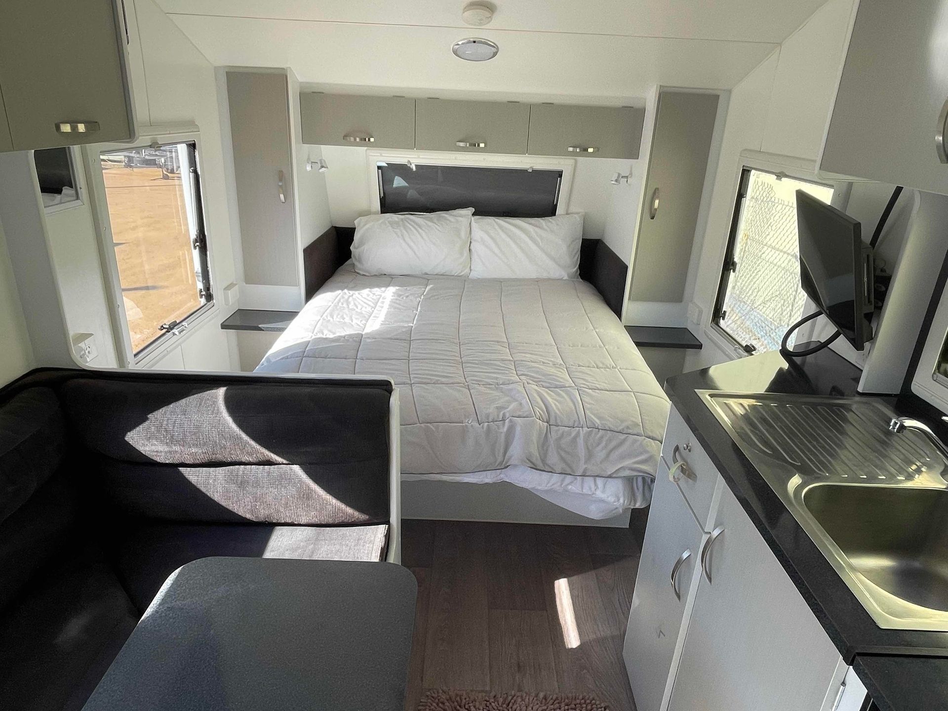 Compact Camper Bedroom with Bed, Sofa, TV, and Kitchenette in A Bright Interior — B & C Caravan Service Pty Ltd In Dubbo, NSW