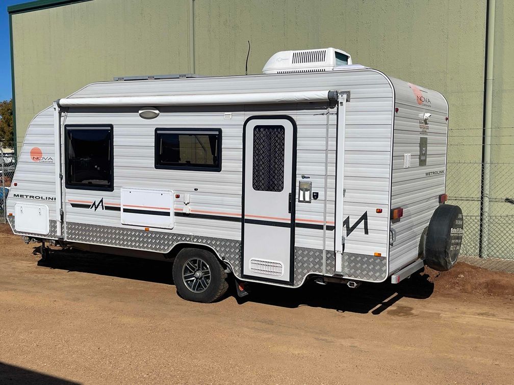 White Travel Trailer Parked on Dirt Beside a Green Wall, with Black Trim and A Roof Vent — B & C Caravan Service Pty Ltd In Dubbo, NSW