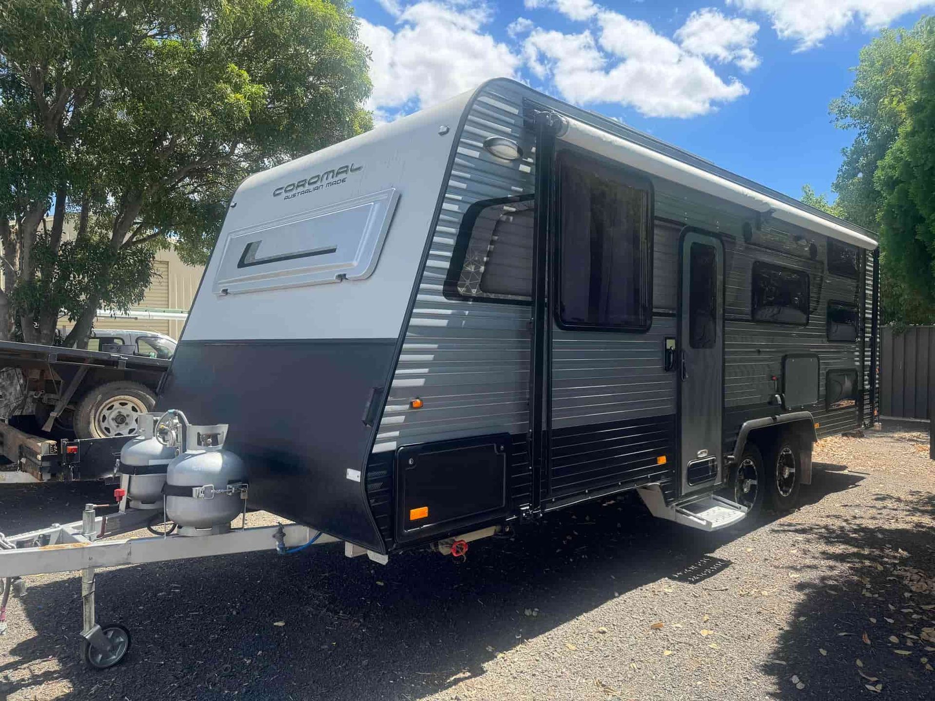 A Caravan is Parked in a Gravel Lot Next to Trees — B & C Caravan Service Pty Ltd In Dubbo, NSW