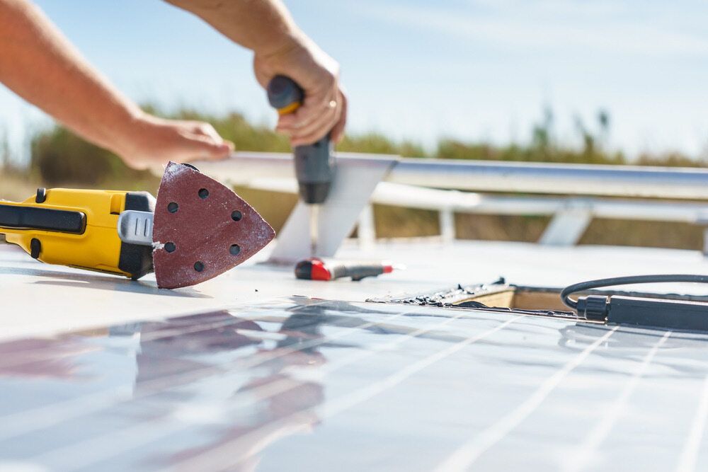 A Person is Working on a Solar Panel With a Drill and Sander — B & C Caravan Service Pty Ltd In Dubbo, NSW