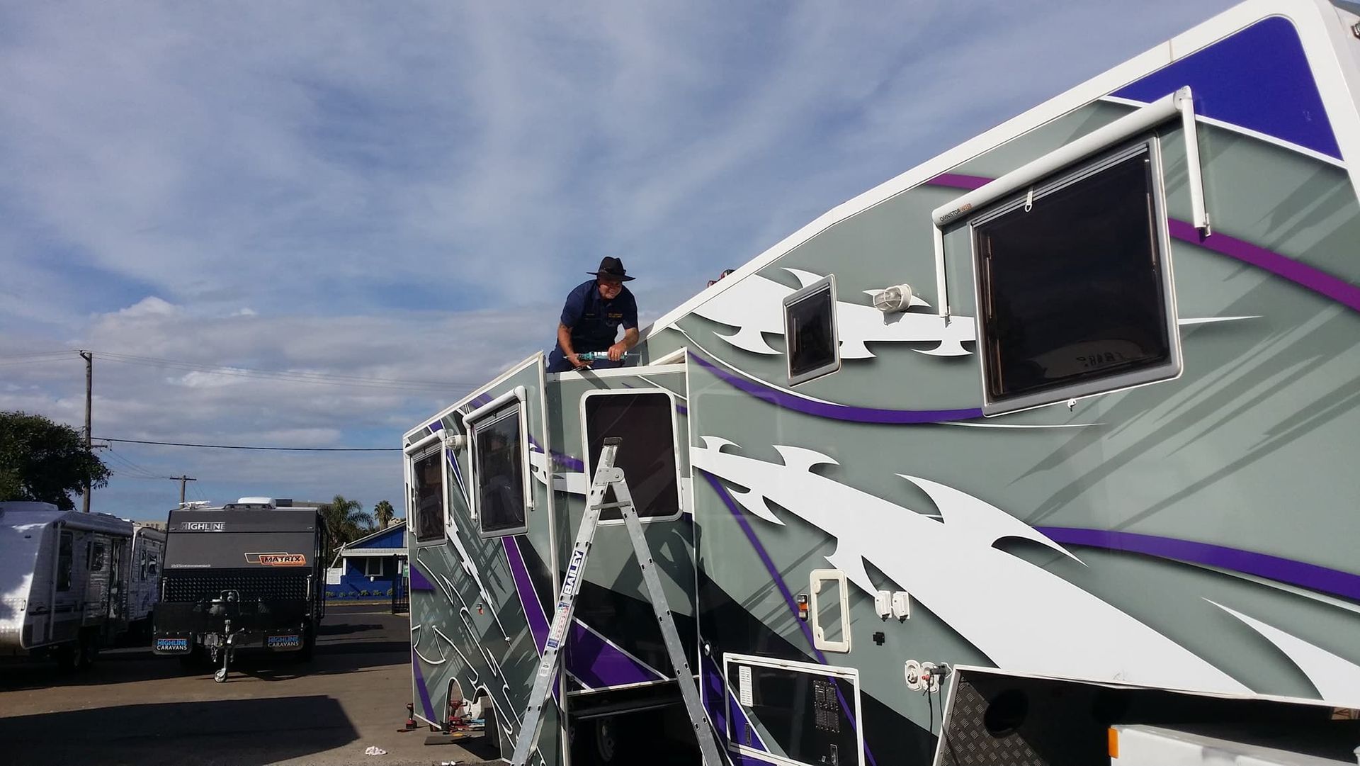 A Man Sitting on Top of a Purple and White RV — B & C Caravan Service Pty Ltd In Dubbo, NSW
