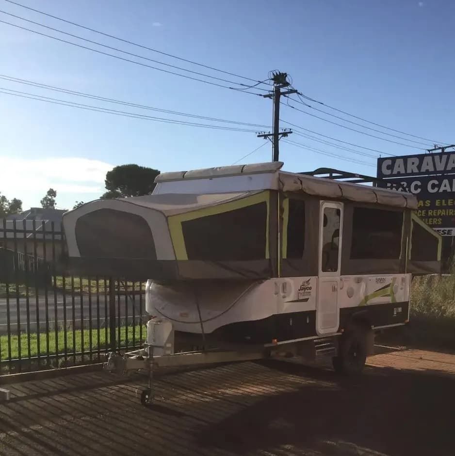 A Caravan is Parked in Front of a Sign That Says Caravan site — B & C Caravan Service Pty Ltd In Dubbo, NSW