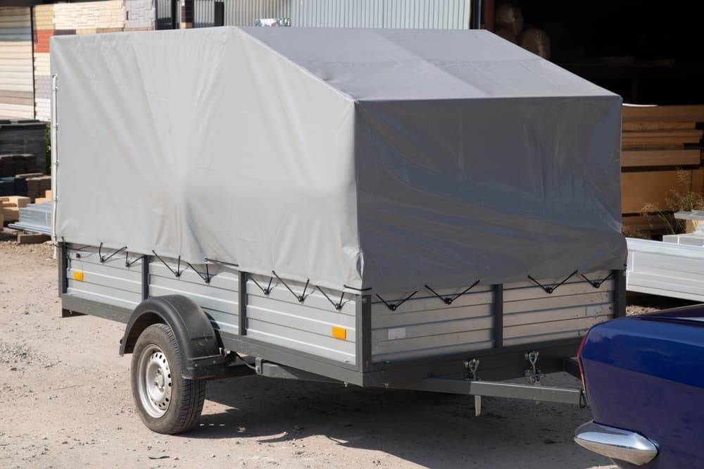 A Trailer With a Canopy is Parked Next to a Blue Car — B & C Caravan Service Pty Ltd In Dubbo, NSW