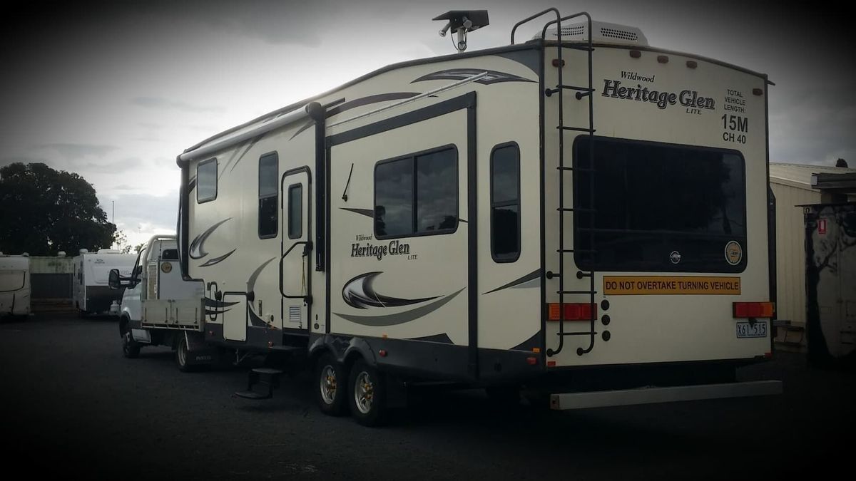 A White RV is Parked in a Parking Lot Next to a Truck — B & C Caravan Service Pty Ltd In Dubbo, NSW
