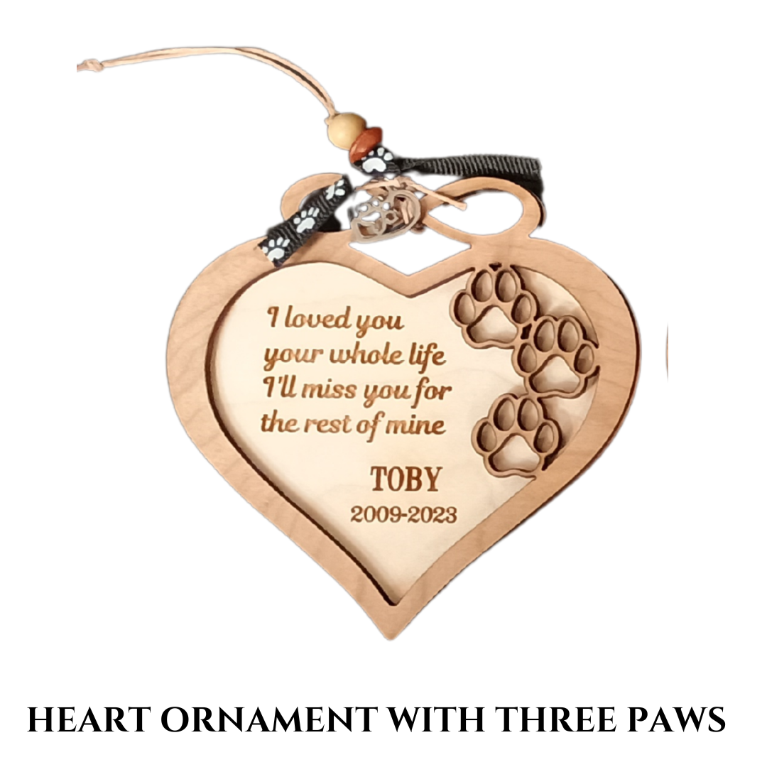 Small, wood heart-shaped ornament with three paw prints, dog's name, birth and death years, and a phrase.