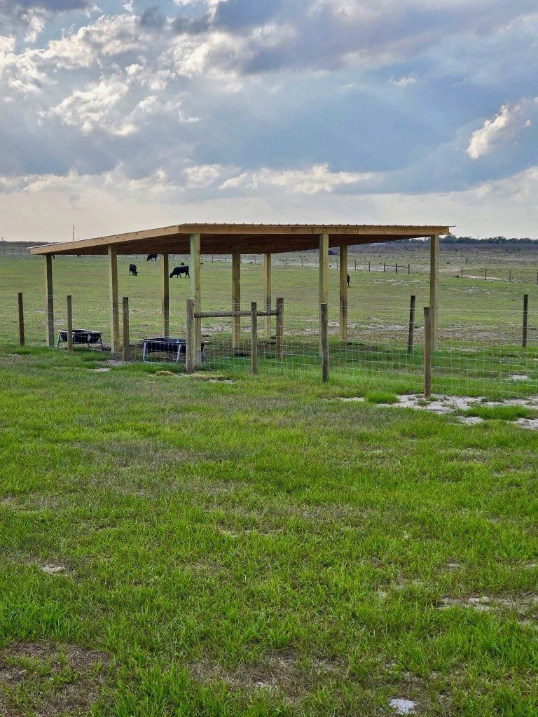 Open field with a small wooden shelter and scattered equipment under a cloudy sky.