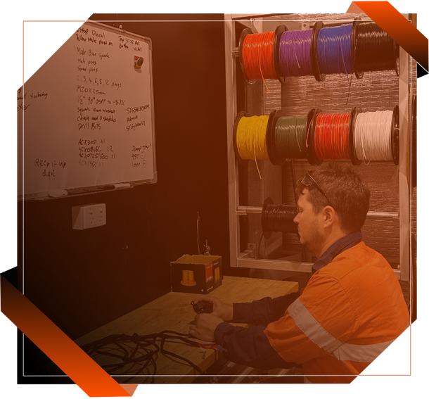 A man is sitting at a desk fabricating a wiring harness for a vacuum truck on the Gold Coast