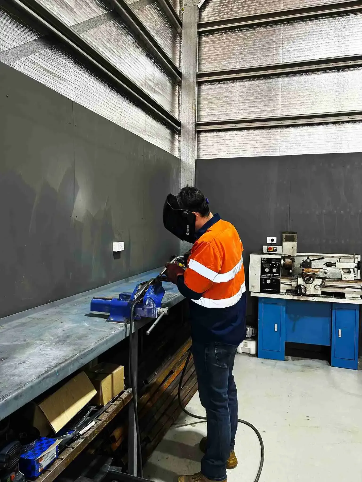 A man wearing a welding helmet welding parts for mine specification service truck