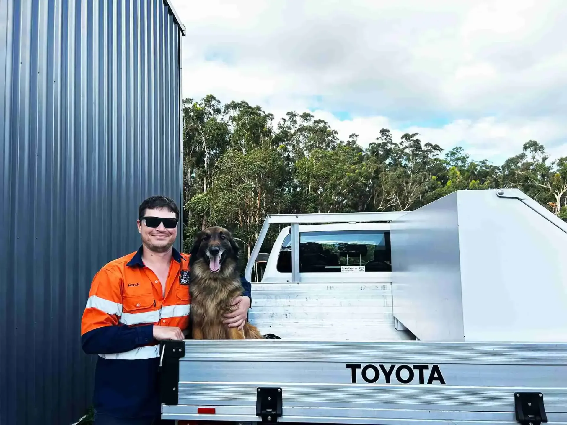 Businessman and a dog are standing next to a Toyota truck.