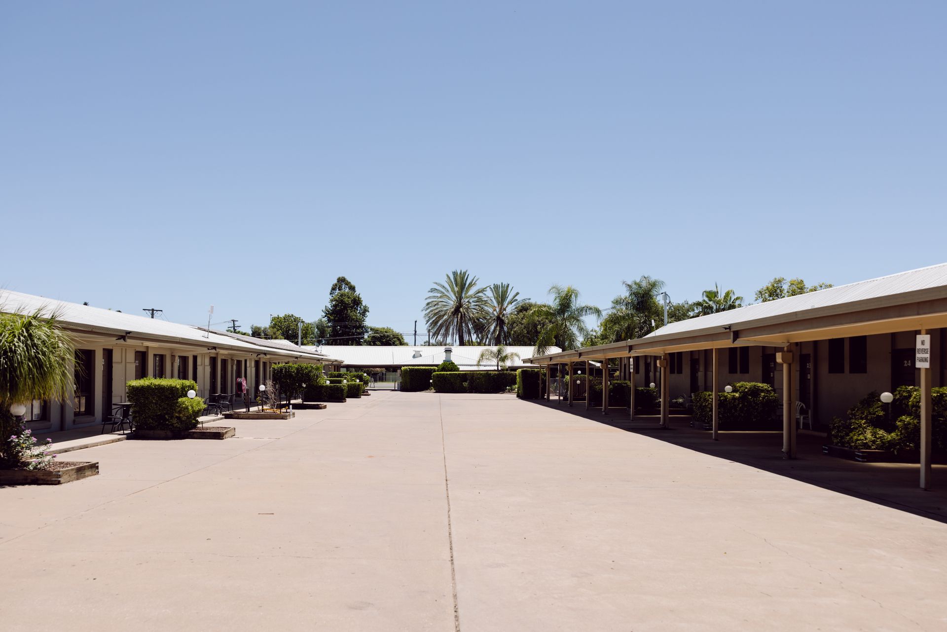 Motel courtyard between single-story buildings under a clear blue sky