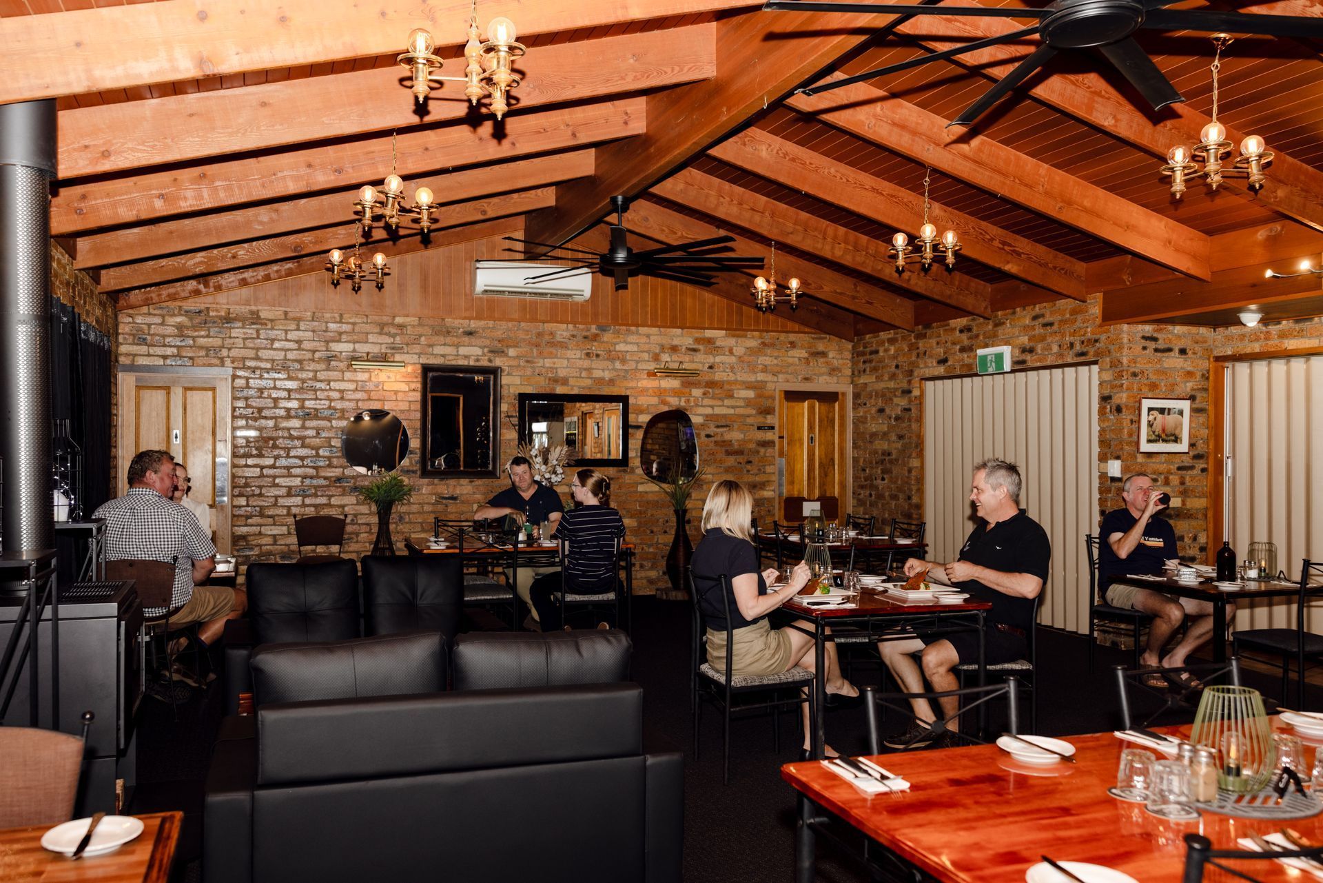 Cozy restaurant interior with exposed wood beams, stone walls, and diners seated at tables