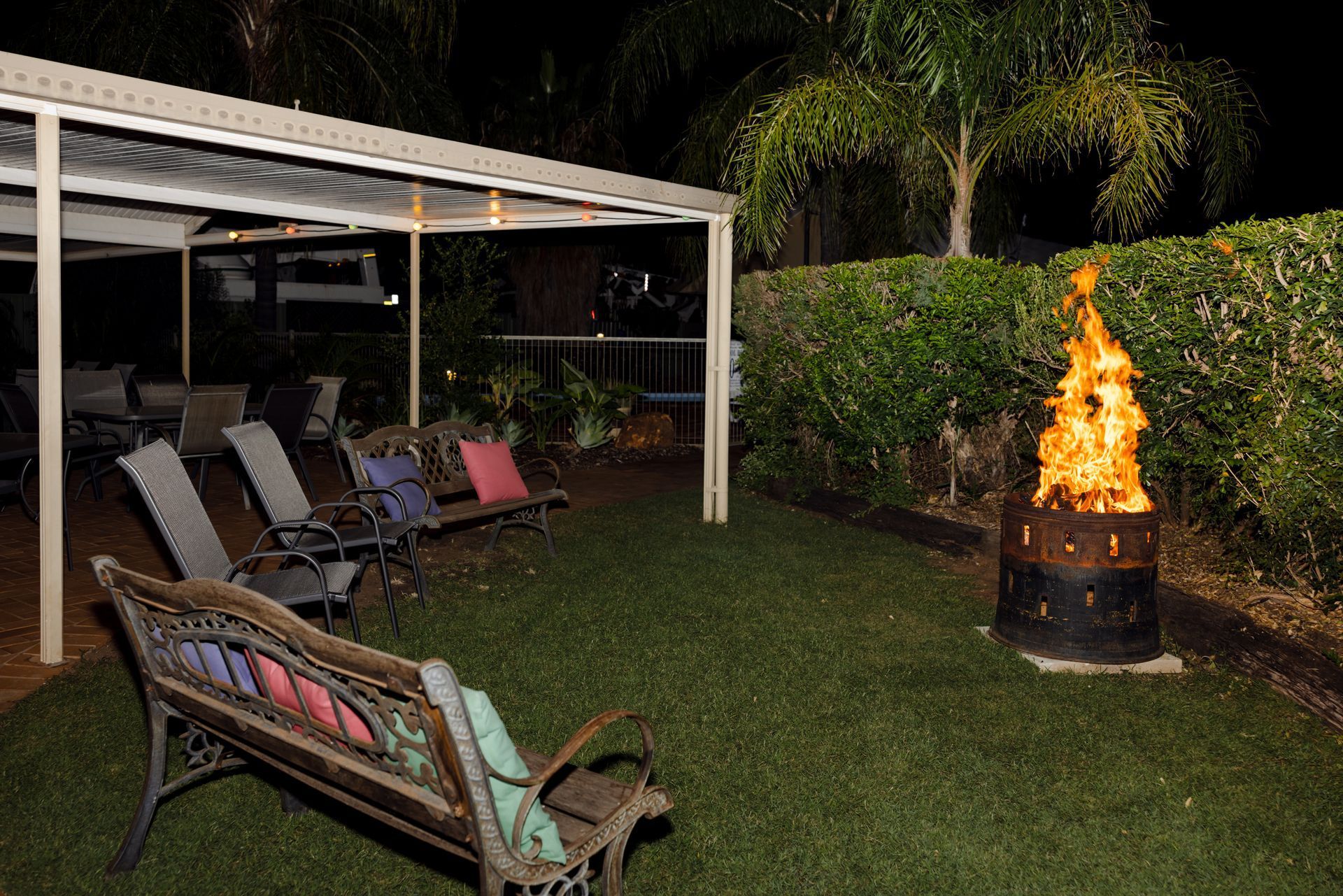 Backyard patio with lounge chairs and a fire pit burning at night