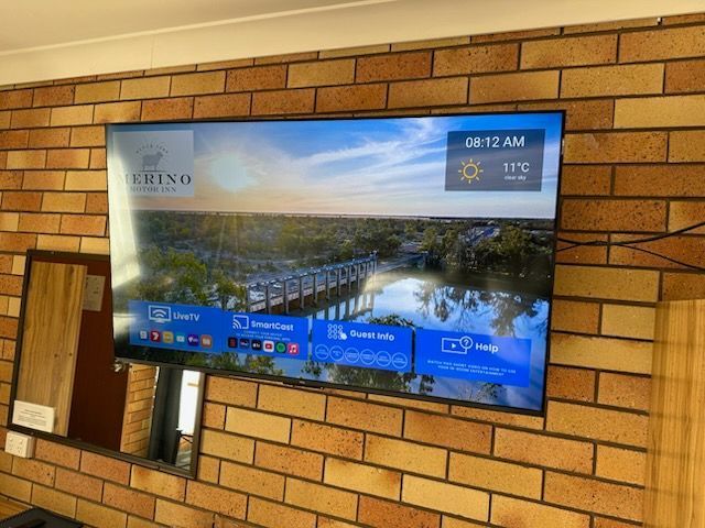 Wall-mounted TV displaying a weather forecast in a brick-walled room