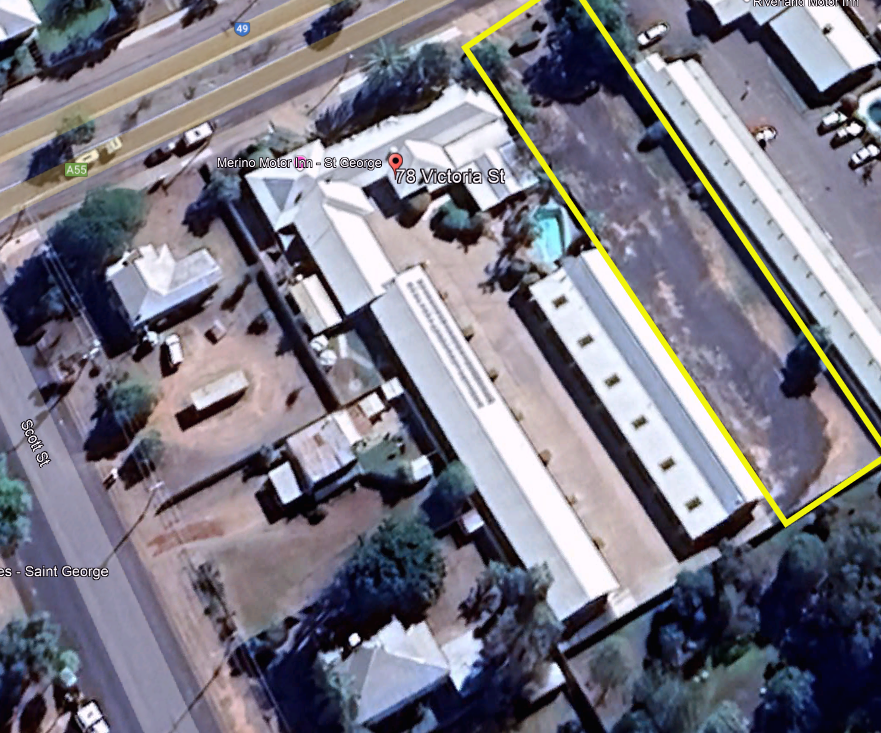 Aerial view of a large building complex, with one long white-roofed section outlined in yellow.