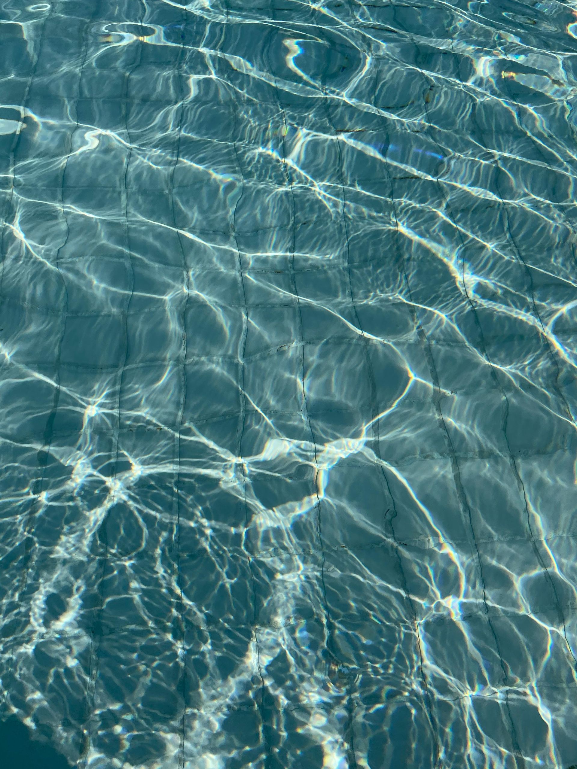 Sunlit blue pool water with shimmering ripples and reflections