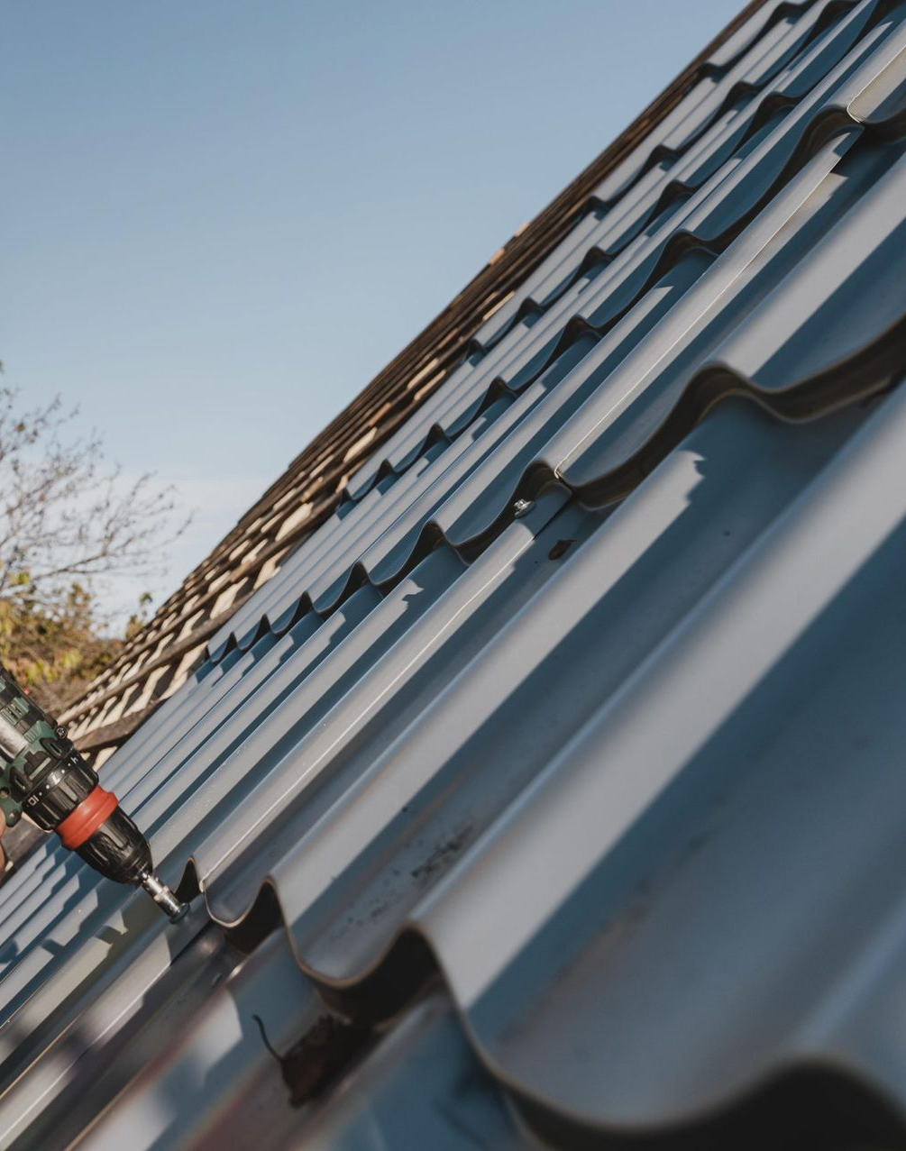 Close-up of a blue metal roof being repaired with a power drill — Southern Trade Services in Warburton, VIC