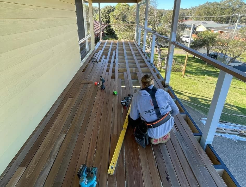 A Woman Is Measuring A Wooden Deck With A Tape Measure — Penman Projects In Salamander Bay, NSW