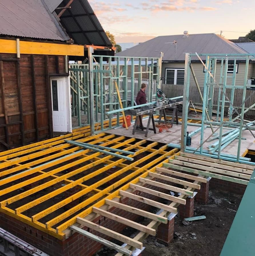 A Man Is Standing On A Wooden Deck In Front Of A House Under Construction — Penman Projects In Shoal Bay, NSW