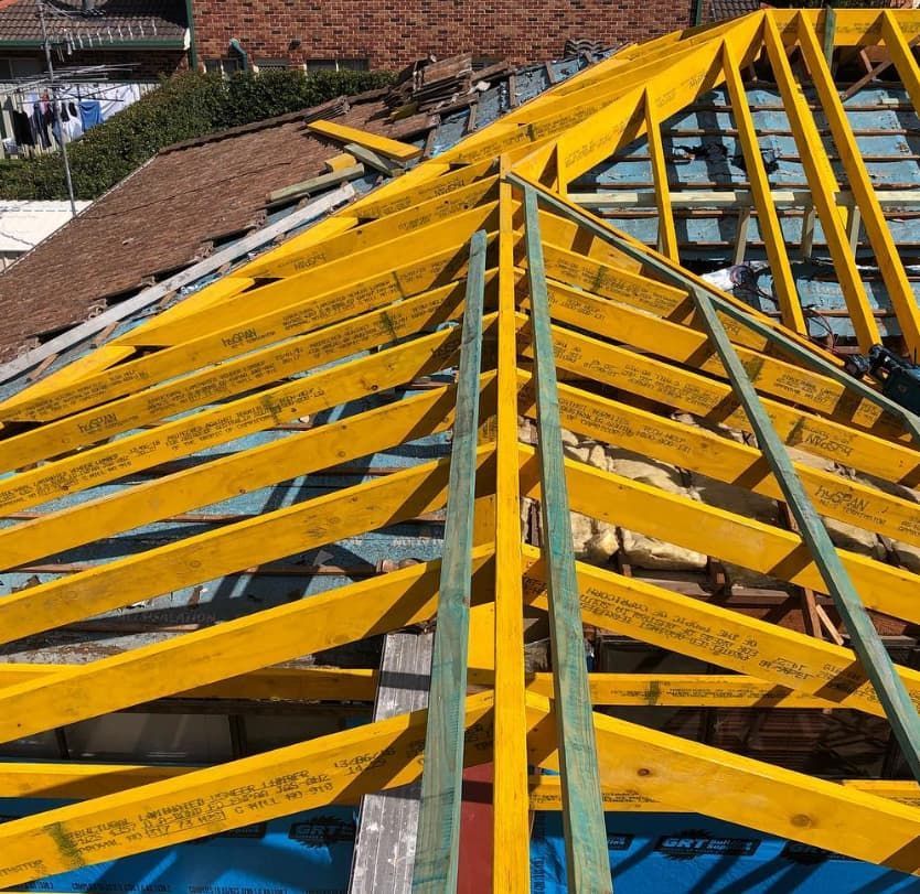 A Roof Is Being Built With Yellow Wooden Beams — Penman Projects In Nelson Bay, NSW