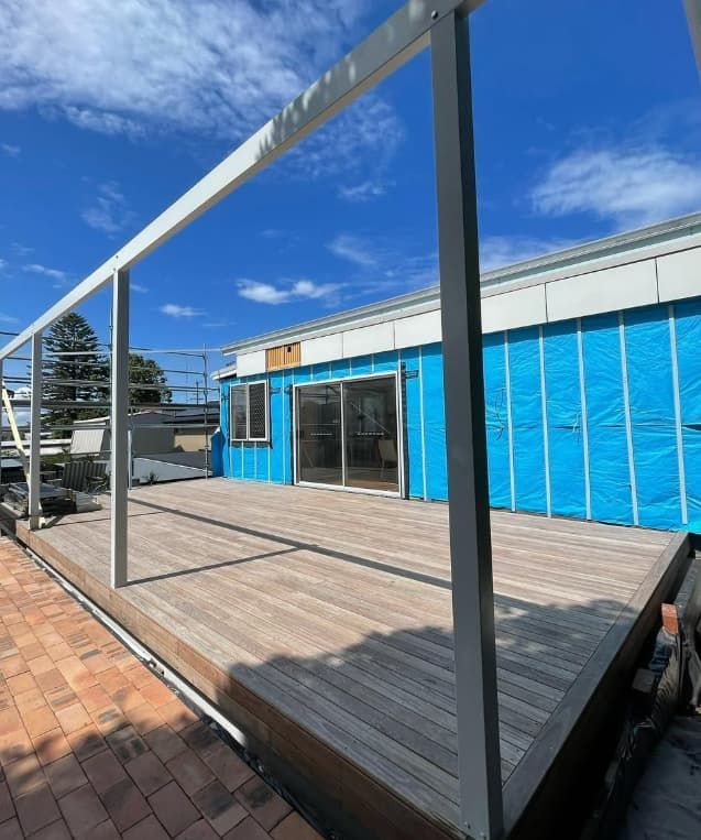 A Blue Building With A Wooden Deck In Front Of It — Penman Projects In Salamander Bay, NSW