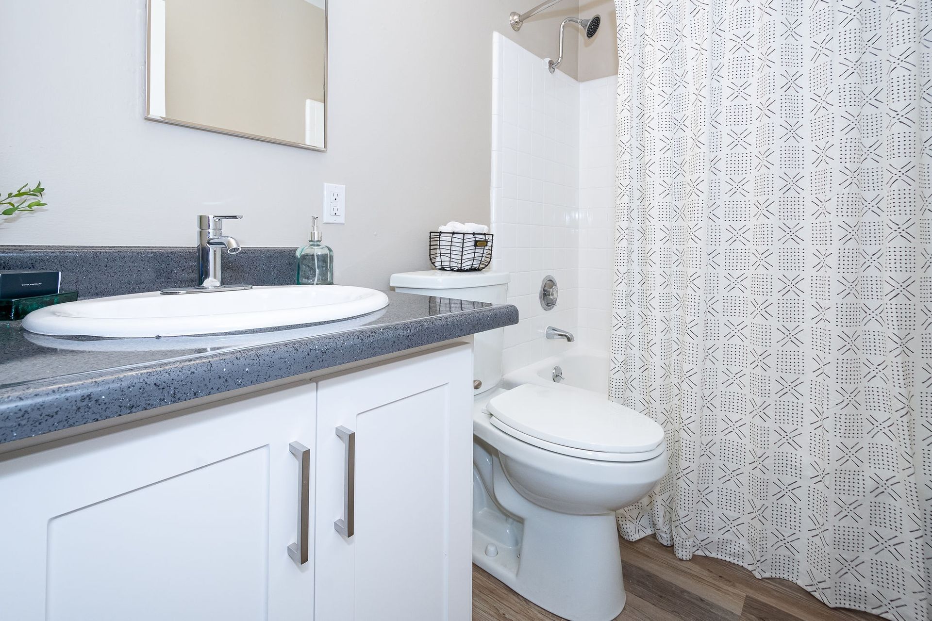 Modern white bathroom with vanity, sink, toilet, and patterned shower curtain