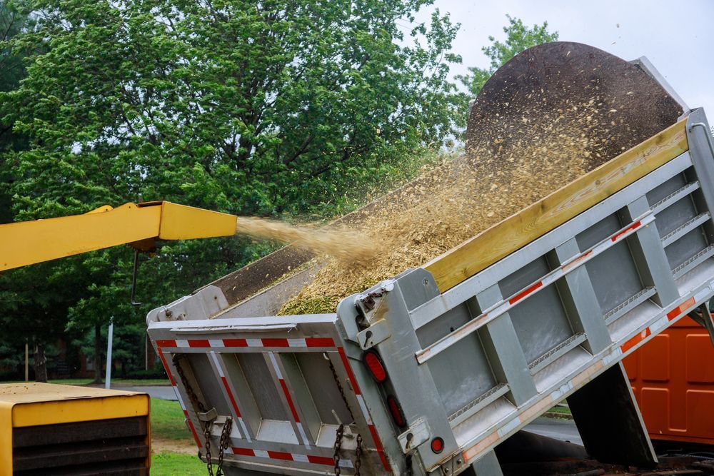 A Dump Truck is Being Loaded With Mulch by a Machine — Tallow Tree Services Pty Ltd in Kyogle, NSW