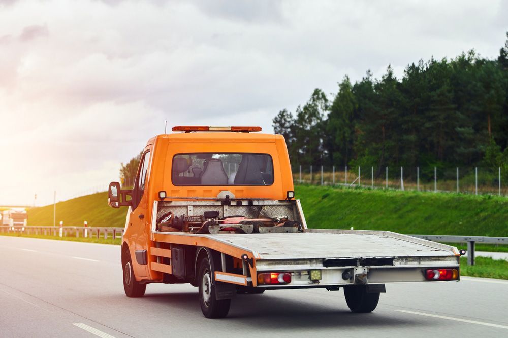An Orange Tow Truck is Driving Down a Highway — Tallow Tree Services Pty Ltd in Lismore, NSW