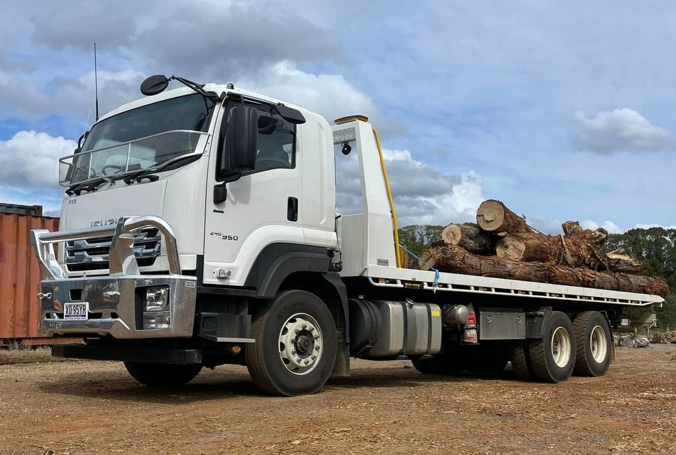 A White Truck is Carrying Logs on the Back of It — Tallow Tree Services Pty Ltd in Lennox Head, NSW
