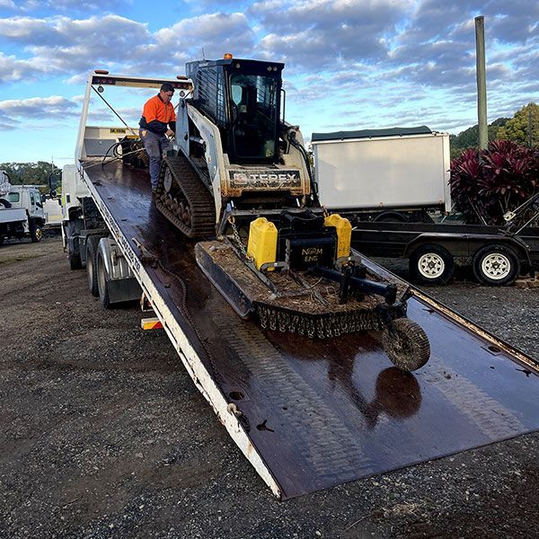 A Man is Loading a Bulldozer on a Tow Truck — Tallow Tree Services Pty Ltd in Bangalow, NSW