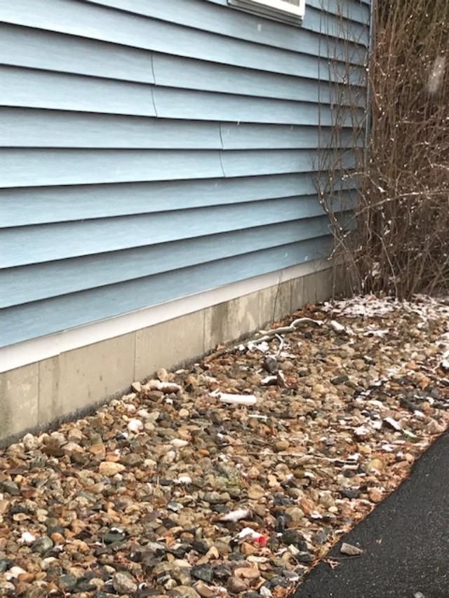 A blue house with a lot of rocks in front of it